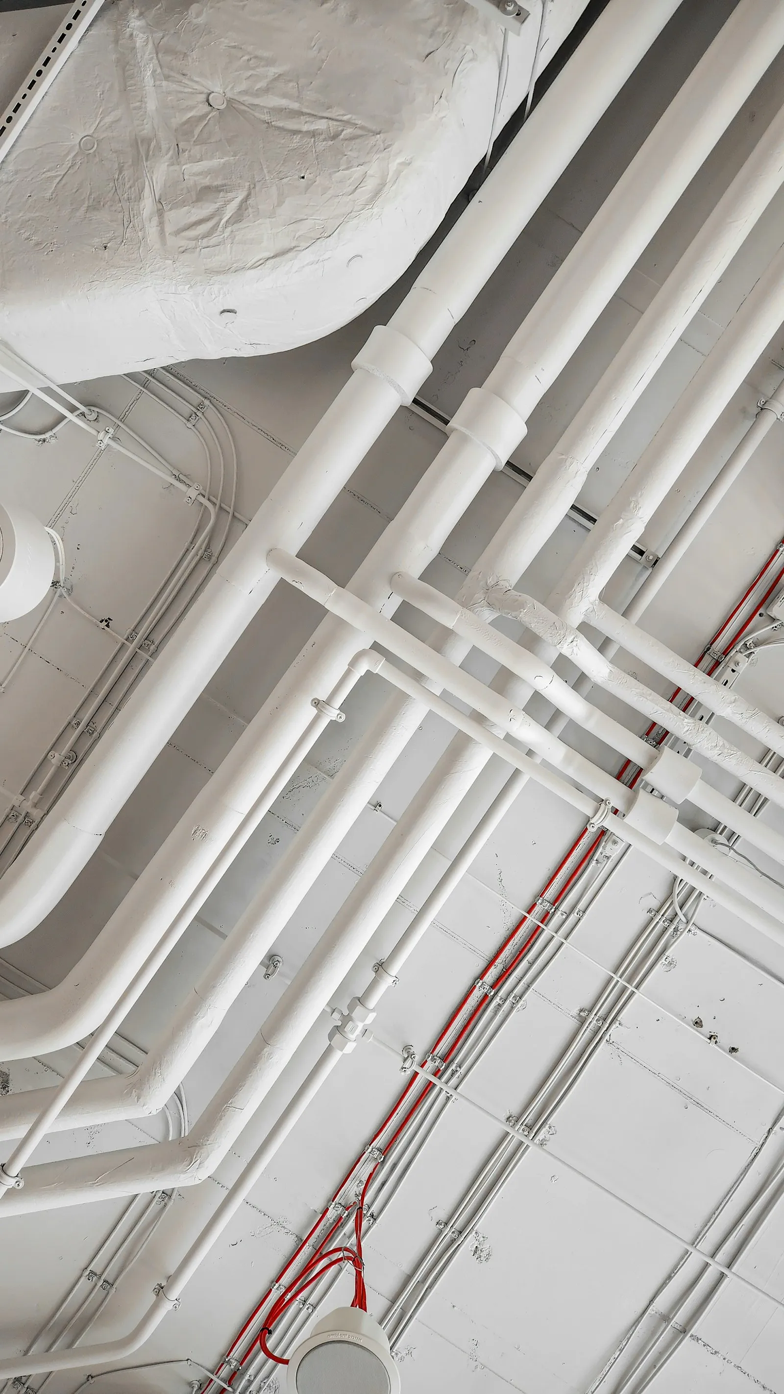 Réseaux de tuyauteries et conduits blancs fixés en plafond, vue en contre-plongée