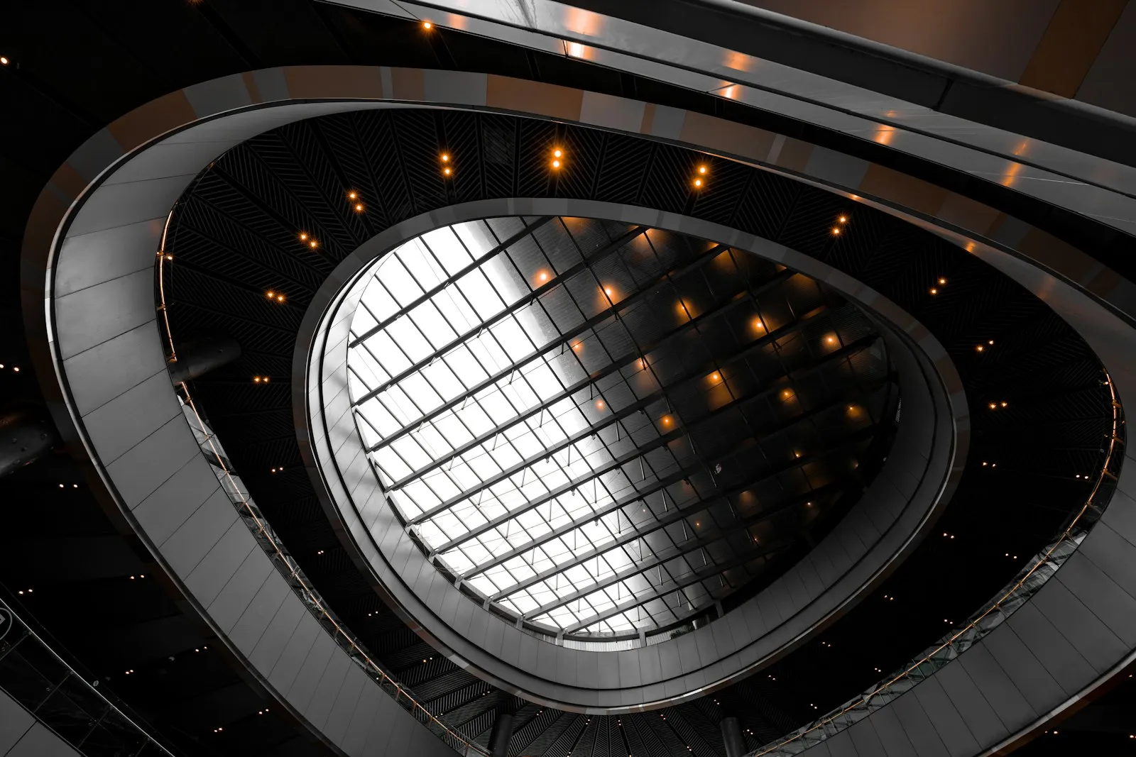 Atrium courbe sous une verrière quadrillée, vu en contre-plongée